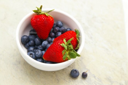 fresh strawberries and blueberries in a bowlの写真素材