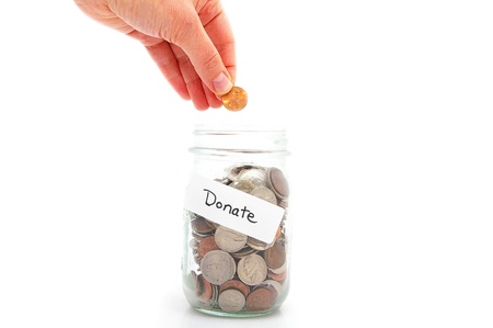 hand putting a penny in a money jar - charity donationの写真素材