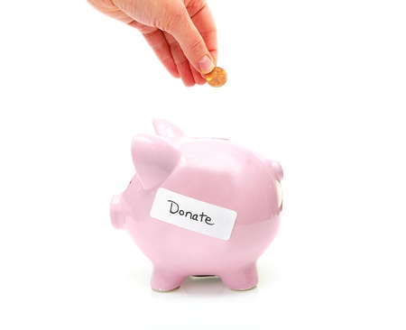 piggy bank with "donate" label and hand with pennyの写真素材