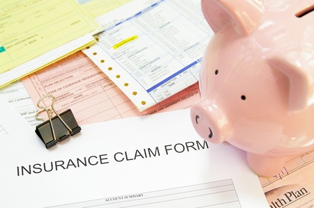 Assorted medical bills and a claim form, with piggy bankの写真素材