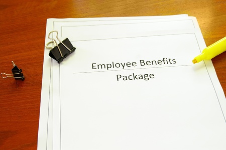 Employee benefits package on a desk with misc office suppliesの写真素材