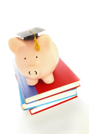piggy bank and graduation cap on books - student debt conceptの写真素材