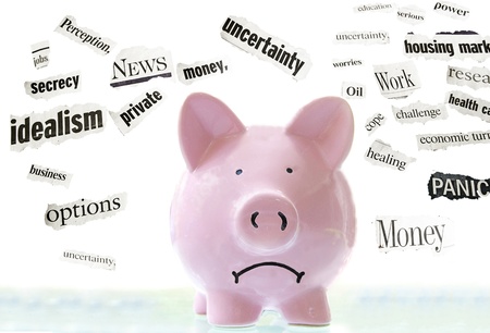 frowning pink piggy bank with bad economic news headlinesの写真素材