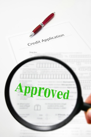 a credit application and magnifying glass with Approved textの写真素材