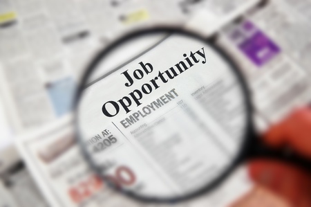 Magnifying glass over a newspaper classified section with  Job Opportunity  textの写真素材