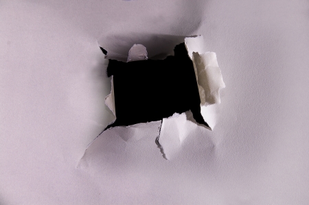 torn hole in a piece of textured paperの写真素材