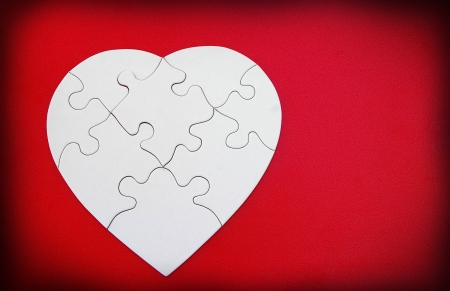 white puzzle shaped heart on red backgroundの写真素材