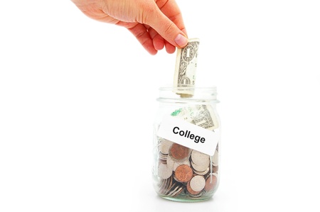 hand putting a dollar into a College savings jarの写真素材