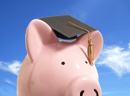 Piggy bank with a graduation cap, against blue skyの写真素材