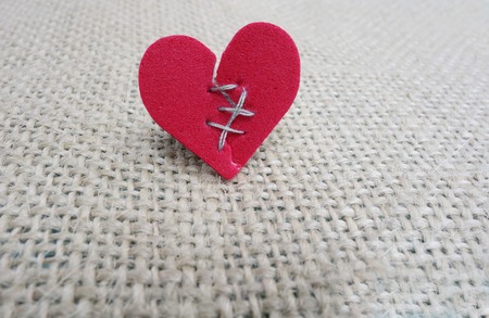 Broken red heart with threaded stitchesの写真素材