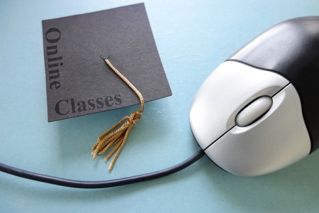 Closeup of a computer mouse and graduation cap - online education conceptの写真素材