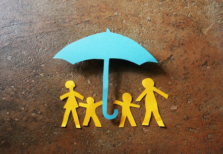 Paper family of four under a paper cutout umbrellaの写真素材