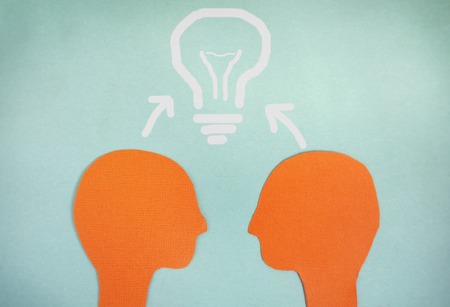 Two paper heads and a light bulb  teamwork conceptの写真素材