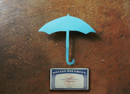 Paper umbrella over a Social Security card  secure retirement conceptの写真素材