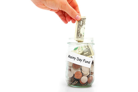 hand putting a dollar into a Rainy Day Fund coin jarの写真素材