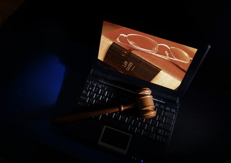 Judge's court gavel on a laptop with law books image on the screenの写真素材