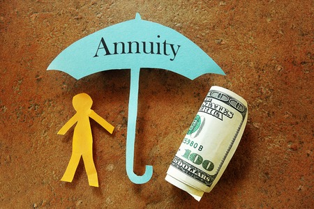 Annuity umbrella over a paper cutout person and hundred dollar billの写真素材