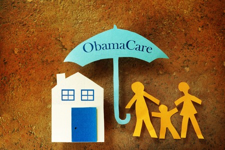 Paper cutout family with house under an Obama Care umbrellaの写真素材