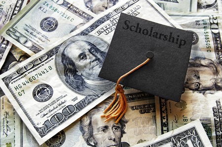 Miniature graduation cap with Scholarship text on hundred dollar billsの写真素材