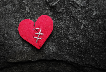 Broken red heart with stitches on textured backgroundの写真素材
