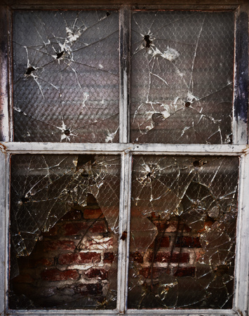 Old broken window with bullet holes and broken glassの写真素材