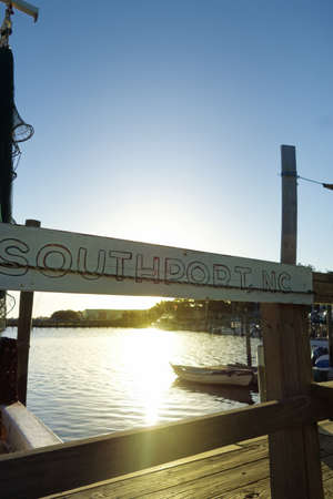 A weathered Southport , NC sign hangs at a dock in the marina on the Cape Fear Riverの写真素材