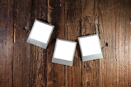 Three blank retro instant camera photos with blank white space on rustic wood backgroundの写真素材