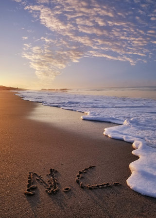 NC written in sand letters at sunrise on the beach in Oak Island North Carolinaの写真素材