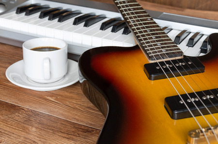 Electro guitar, piano and cap of coffee. Break during rehearsal