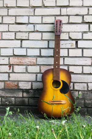 Acoustic guitar resting against a white brick wall with copy spaceの写真素材
