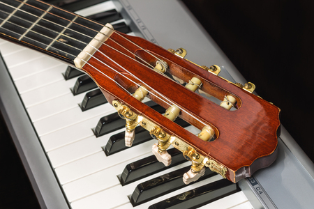 Guitar headstock on the piano keyboard, close upの写真素材