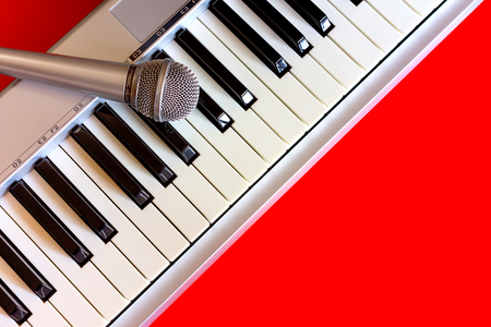 Top view on digital piano keyboard with microphone on the red bacgroundの写真素材