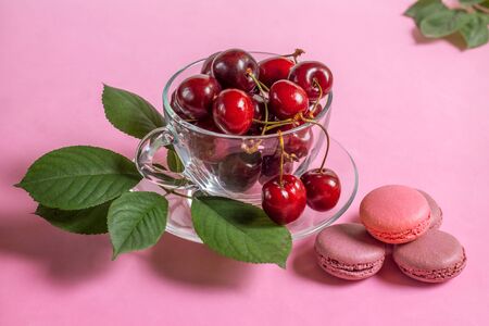 Cherries in the glass cup with macaroons and leaves