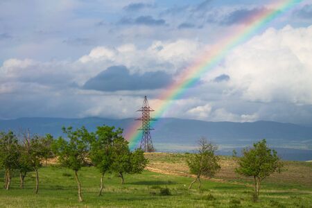 Beautiful landscape with rainbow over power pylonの写真素材
