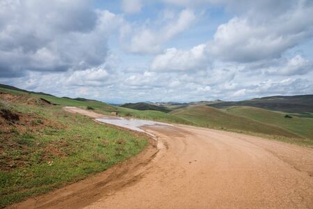 Country road in the mountains with cloudy sky