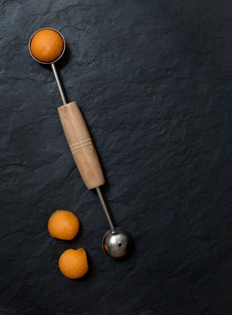 Melon balls with melon baller on stone backgroundの写真素材