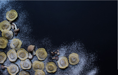 Homemade tortellini with mushrooms on black background. Top viewの写真素材