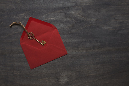 Open red envelope on dark wood background with keyの写真素材