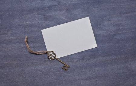 Invitation card with key on wooden background