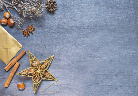 Christmas background with golden star, envelope, nut, cinnamon and glitter decoration on dark wooden background. Top viewの写真素材