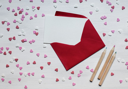 Red envelope with a lot of hearts on white wooden background. Top viewの写真素材
