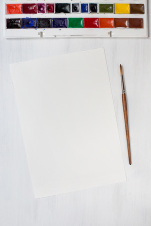 Watercolor paintbrushe with colors on white wooden background. Top view.の写真素材