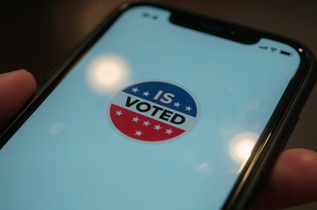A person displays the I Voted sticker on their phone, promoting civic engagement and voter turnout. Ideal for election campaigns and social media.の素材