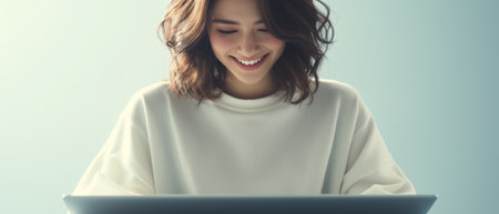 Happy latin woman using laptop device on blue background. Smiling female model holding computer, advertising job search or shopping website, online services concept.の素材