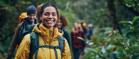Walking in woods with multiethnic friends. Smiling woman enjoying hiking with hikers on wild trail among green trees. Copy space.の素材