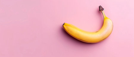 In this flat lay, bananas are placed on a pastel pink background.の素材