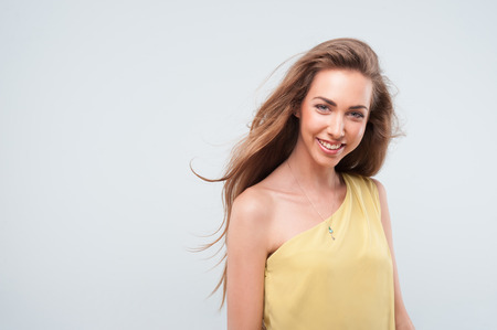 Emotional attractive young dark-blonde woman standing in half length at the blue wall backgroundの写真素材