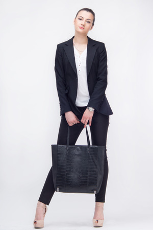 Nice young businesswoman with bag standing in full length, isolated on white backgroundの写真素材