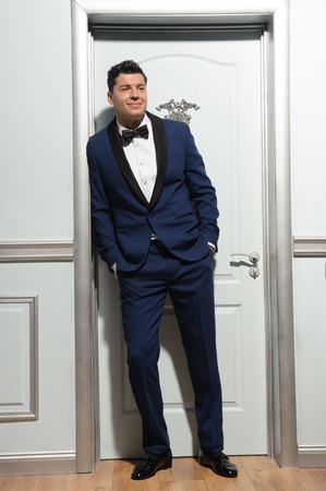 Full length portrait of handsome business leader looking aside on room interior backgroundの写真素材