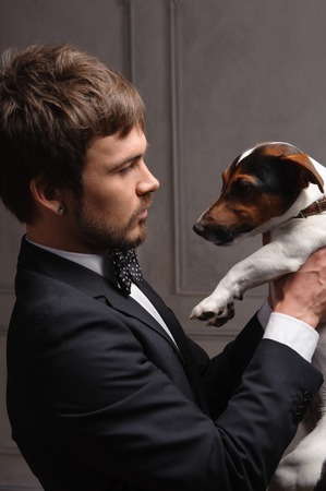 Portrait of a man holding a jack Russell terrier dog on indoor backgroundの写真素材